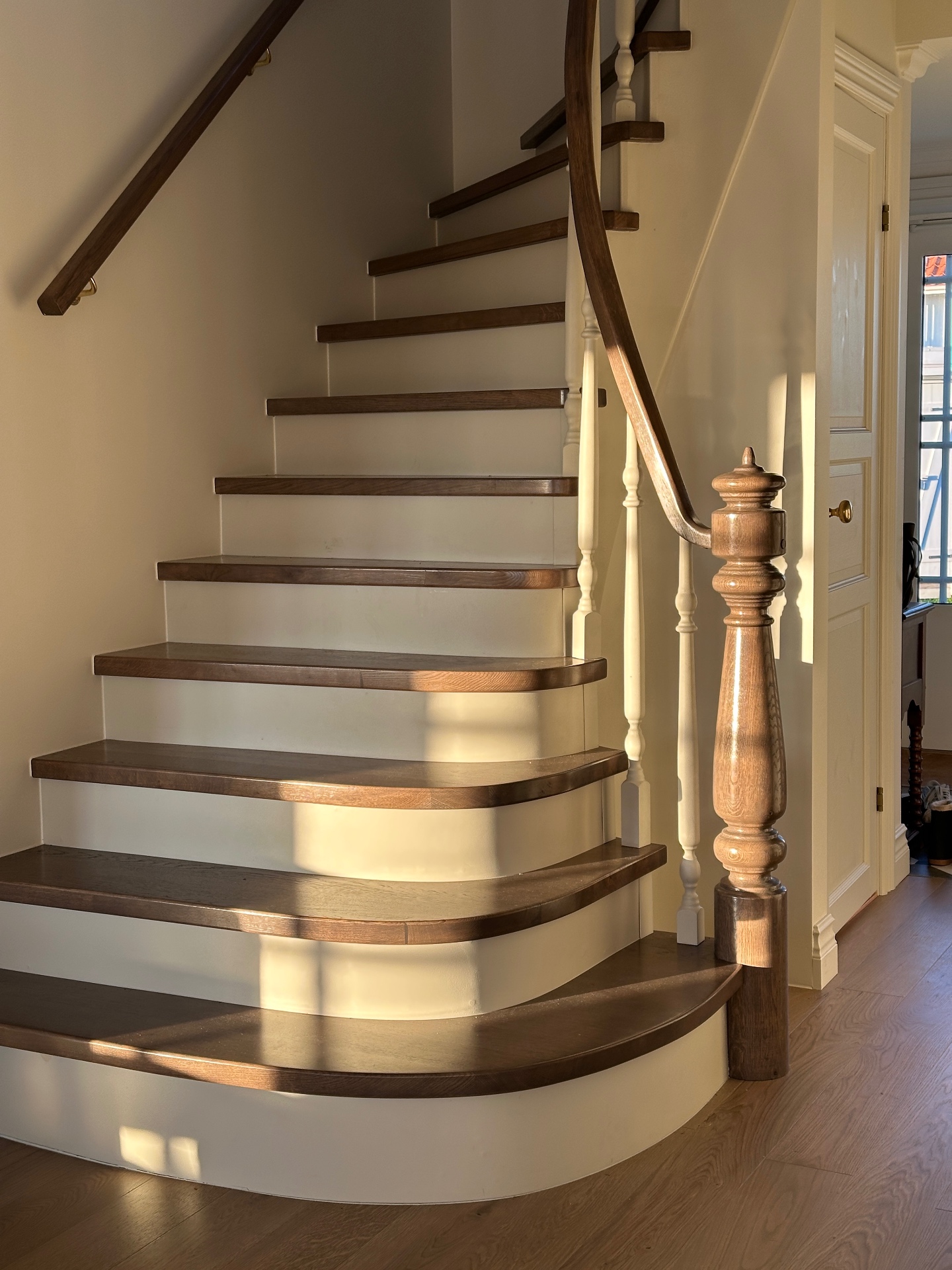 Built-in staircase with dark oak treads and curved handrail