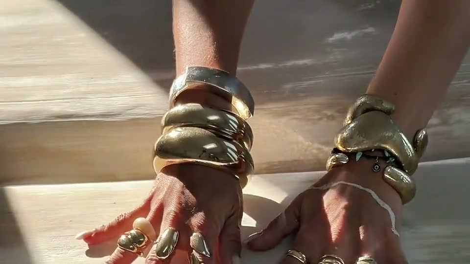 Martina Braun's hands moving over a textured artwork in sunlight