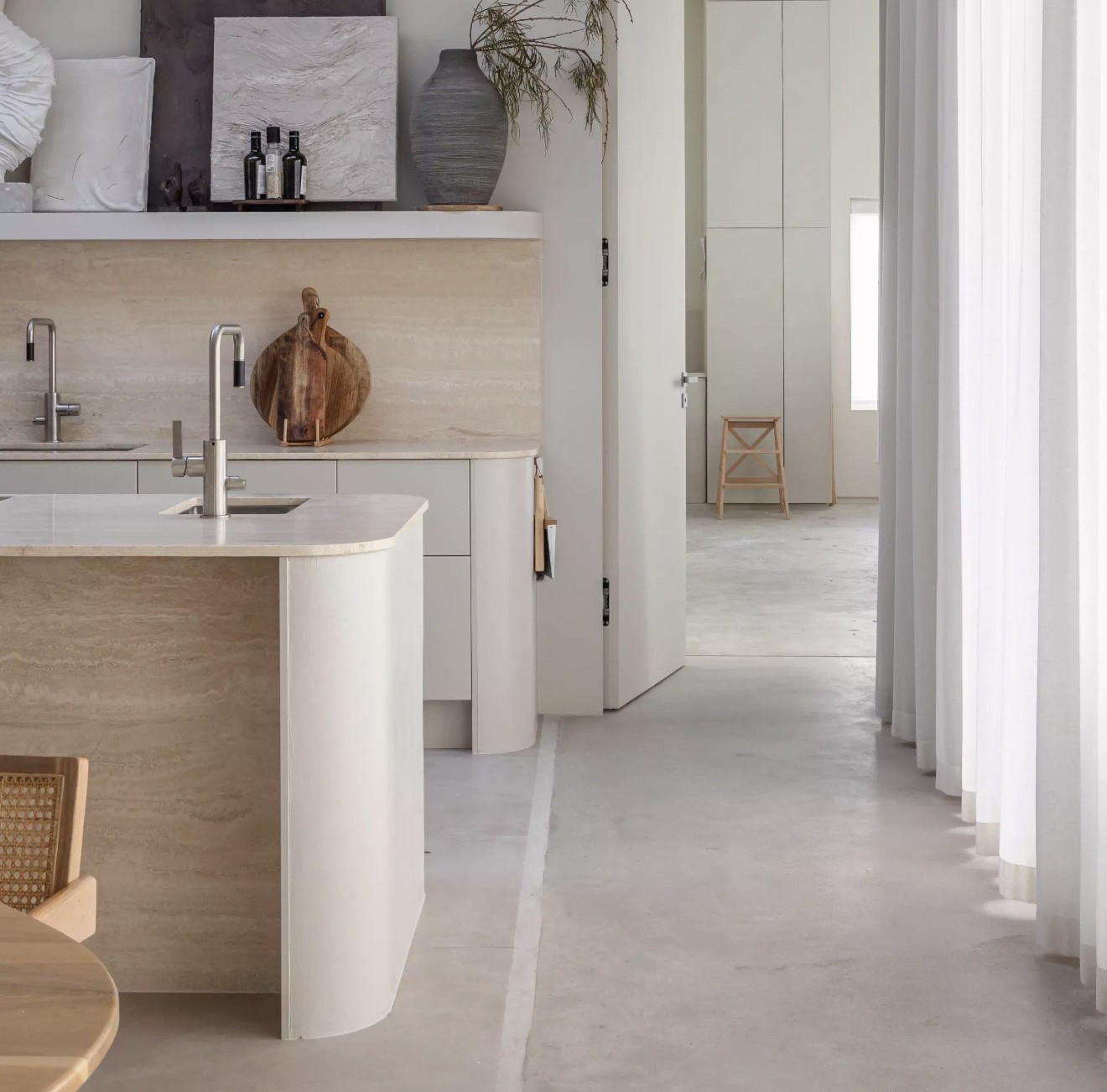 Built-in kitchen with curved travertine island and plaster hood